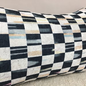Puede incluir: Una almohada de tiro a cuadros en blanco y negro con un sutil brillo iridiscente. La almohada tiene un patr&oacute;n geom&eacute;trico con una ligera variaci&oacute;n en el ancho de las rayas.