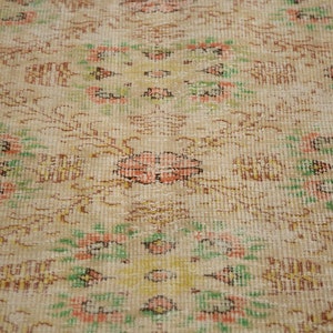 May include: A vintage rug with a cream background and a floral pattern in shades of pink, green, and brown.