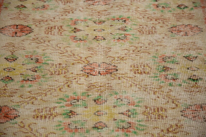 May include: A vintage rug with a cream background and a floral pattern in shades of pink, green, and brown.
