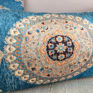 May include: A blue and orange patterned throw pillow with a large, intricate design in the center.