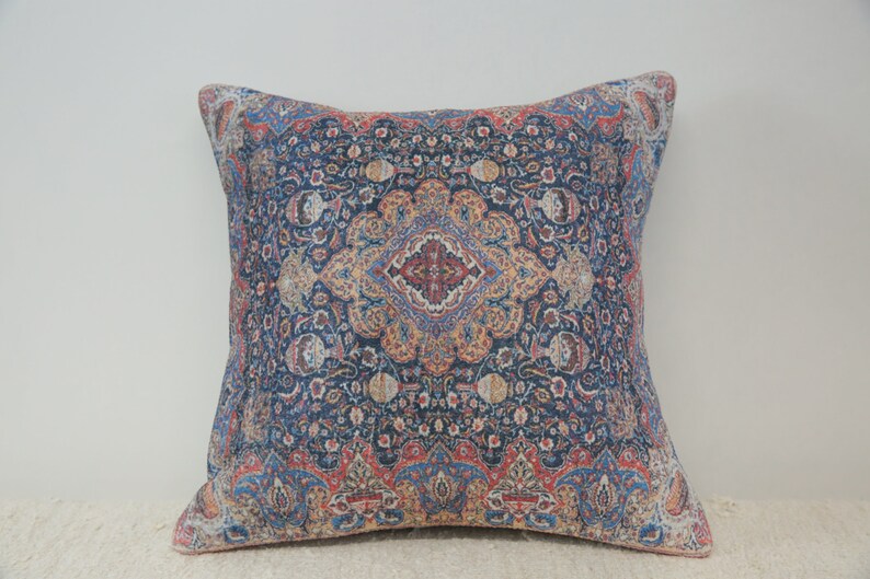May include: A decorative throw pillow with a blue, red, and gold patterned design. The pattern is intricate and features a floral motif.