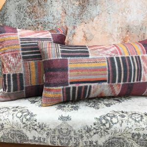 Puede incluir: Dos almohadas decorativas con un diseño de patchwork que presenta una variedad de colores y patrones, incluyendo burdeos, negro, blanco y dorado.