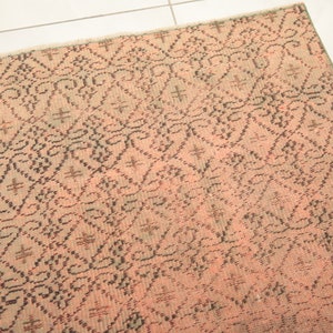 May include: A pink and black patterned rug with a geometric design. The rug has a distressed look and is made of a woven material.