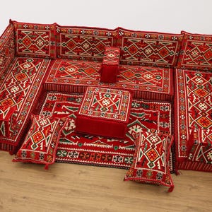 Peut inclure: Un canapé sectionnel rouge et blanc à motifs avec des coussins assortis et un ottoman central. Le canapé présente un motif géométrique avec des franges, créant un coin salon accueillant.