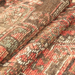 a close-up view of a colorful, intricately patterned rug or carpet with a mix of red, orange, and brown hues.
