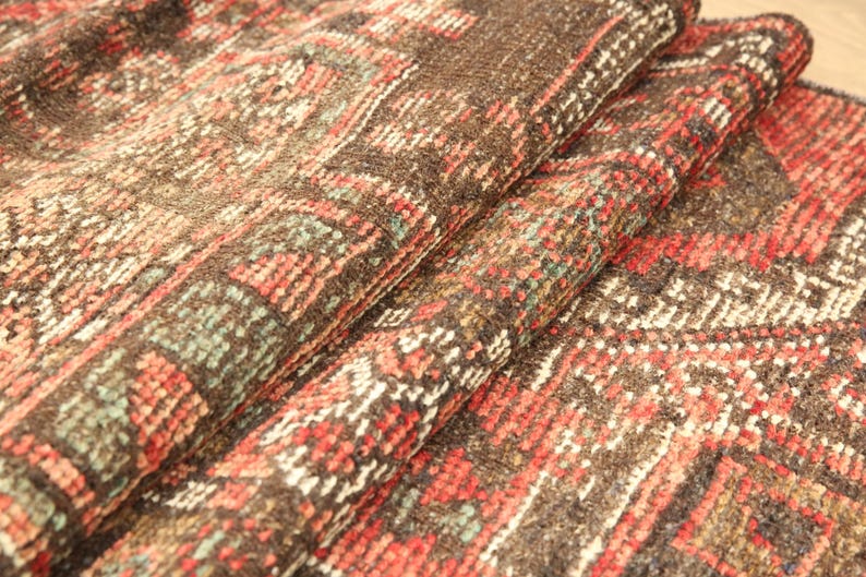 a close-up view of a colorful, intricately patterned rug or carpet with a mix of red, orange, and brown hues.