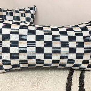 Puede incluir: Dos almohadas decorativas con un patr&oacute;n de cuadros negros y blancos. La tela tiene un brillo iridiscente sutil y presenta finas rayas beige, rosa y azul.