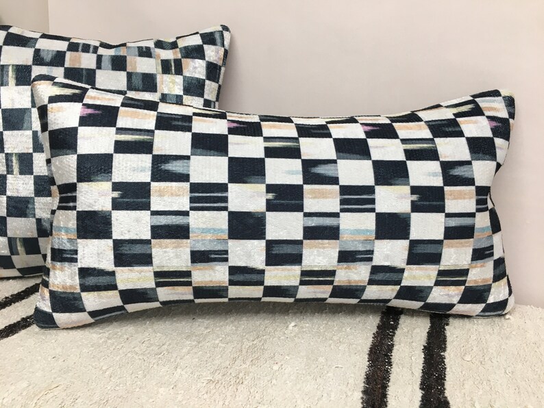 Puede incluir: Dos almohadas decorativas con un patr&oacute;n de cuadros negros y blancos. La tela tiene un brillo iridiscente sutil y presenta finas rayas beige, rosa y azul.
