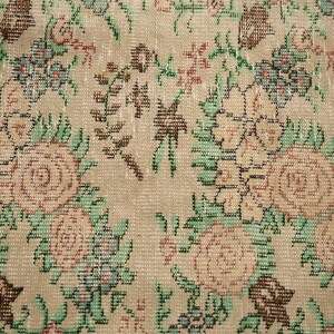 May include: Close-up of a beige rug with a floral pattern. The rug features a repeating design of pink and white roses with green leaves.