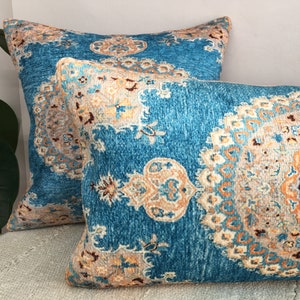 May include: Two decorative throw pillows with a blue background and intricate patterns in shades of orange, brown, and white.
