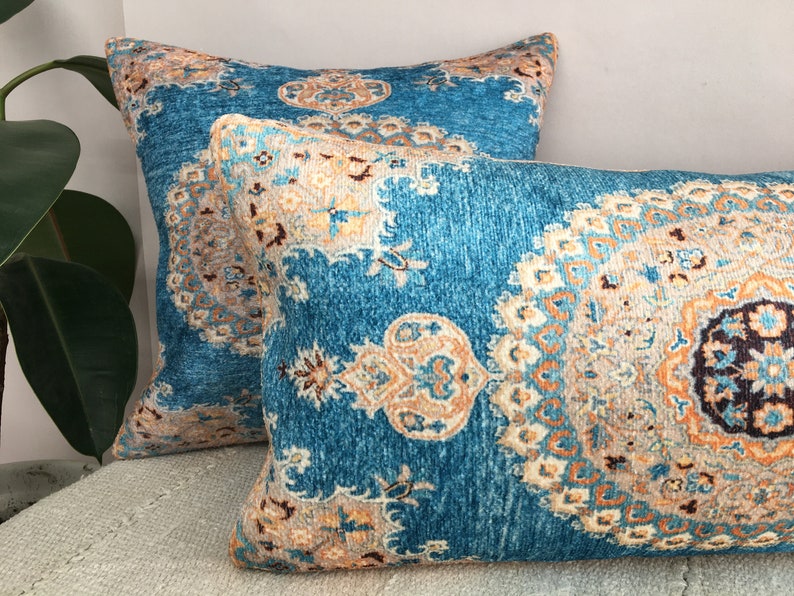 May include: Two decorative throw pillows with a blue background and intricate patterns in shades of orange, brown, and white.