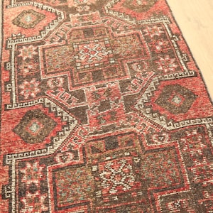 a colorful, intricately patterned rug with a geometric design in shades of red, black, and white.