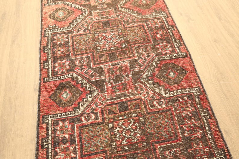 a colorful, intricately patterned rug with a geometric design in shades of red, black, and white.