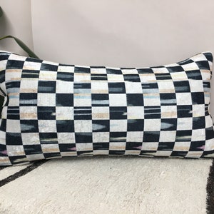 Puede incluir: Una almohada de tiro a cuadros en blanco y negro con un sutil patr&oacute;n ikat. La almohada est&aacute; hecha de una tela suave y lujosa y tiene un dise&ntilde;o moderno y &uacute;nico.