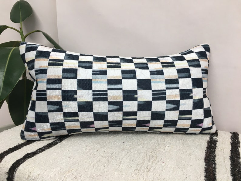 Puede incluir: Una almohada de tiro a cuadros en blanco y negro con un sutil patr&oacute;n ikat. La almohada est&aacute; hecha de una tela suave y lujosa y tiene un dise&ntilde;o moderno y &uacute;nico.