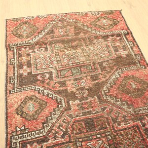a vibrant, intricately patterned rug with a mix of red, brown, and black colors, featuring geometric designs and floral motifs.