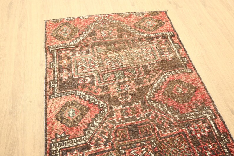a vibrant, intricately patterned rug with a mix of red, brown, and black colors, featuring geometric designs and floral motifs.