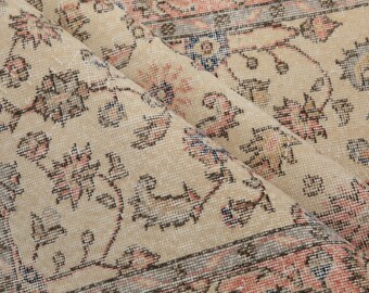 Puede incluir: Primer plano de una alfombra beige con un patrón floral. La alfombra tiene una sutil combinación de colores rosa y azul y un diseño detallado.