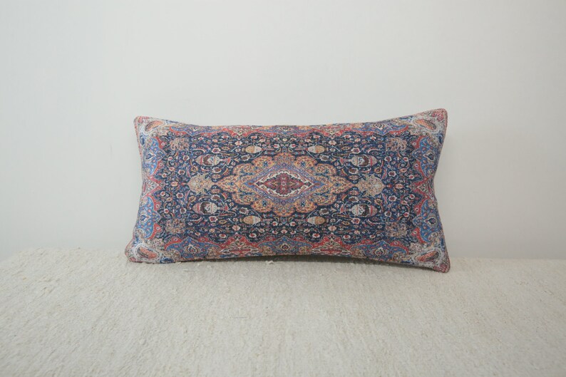 May include: A decorative pillow with a blue, red, and orange patterned design. The pattern is reminiscent of a traditional rug.