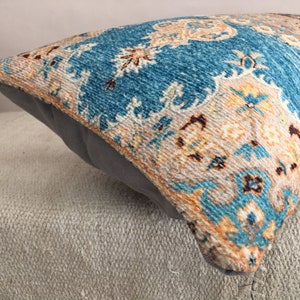 May include: A blue and beige patterned throw pillow with a fringe border. The pillow is made of a soft, woven fabric and has a subtle sheen.