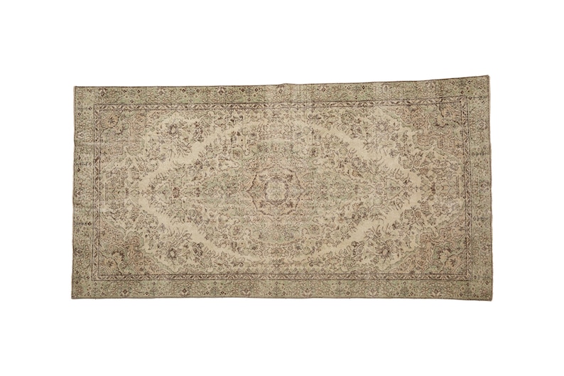 K&ouml;nnte beinhalten: Ein Vintage-Teppich mit beigefarbenem Hintergrund und einem floralen Muster in Braun- und Gr&uuml;nt&ouml;nen. Der Teppich hat einen Rand mit einem sich wiederholenden Muster.