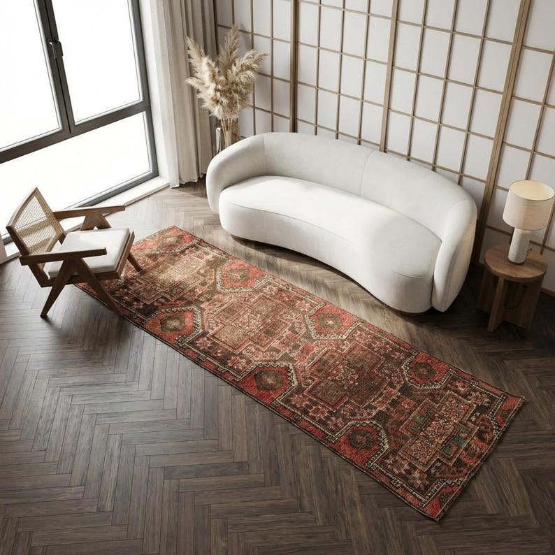 a modern living room with a white sofa, a wooden chair, a large rug, and a large window.