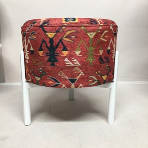 Puede incluir: Un puf rojo y blanco con estampado con cuatro patas blancas. El puf tiene un dise&ntilde;o geom&eacute;trico con colores rojo, blanco, negro, amarillo y verde.