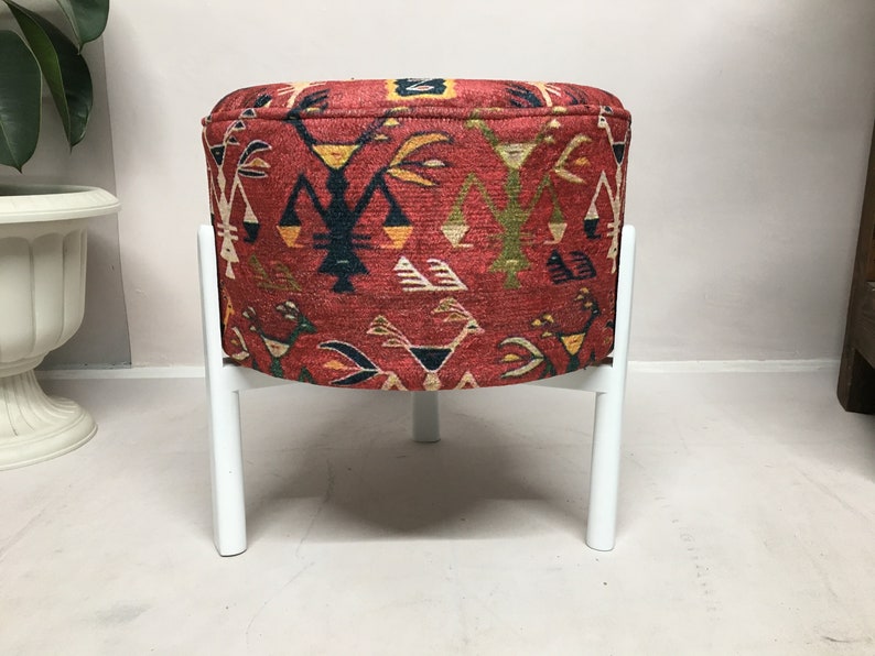 Puede incluir: Un puf rojo y blanco con estampado con cuatro patas blancas. El puf tiene un dise&ntilde;o geom&eacute;trico con colores rojo, blanco, negro, amarillo y verde.