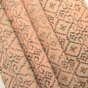 May include: A folded pink and brown patterned rug with a fringed edge.