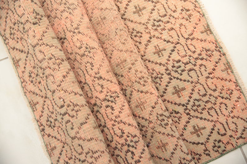 May include: A folded pink and brown patterned rug with a fringed edge.