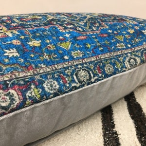 May include: A blue and white patterned throw pillow with a gray border. The pillow is made of a soft, plush fabric and has a subtle sheen.