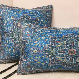 May include: Two decorative throw pillows with a blue and white patterned design. The pillows have a geometric pattern with a central medallion.