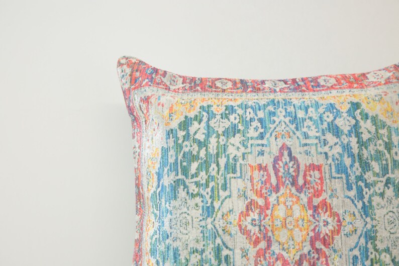 May include: A colorful throw pillow with a patterned design featuring shades of blue, green, red, yellow, and white.