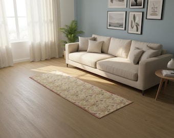 May include: A rectangular area rug featuring a cream-colored base with a multi-colored floral pattern in shades of red, blue, and green. The rug is positioned on a light-toned wooden floor in front of a beige sofa with several matching throw pillows.