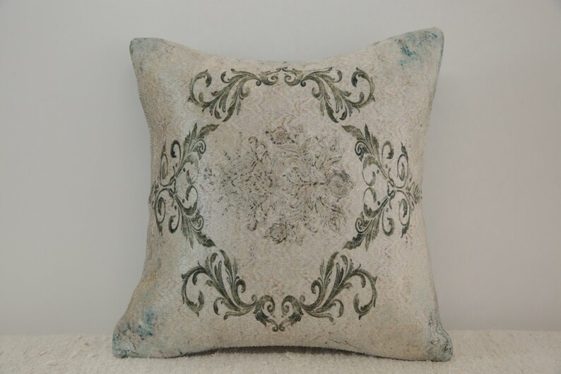 Puede incluir: Una almohada blanca con un patr&oacute;n floral verde. La almohada tiene un aspecto desgastado y est&aacute; hecha de una tela suave y texturizada.