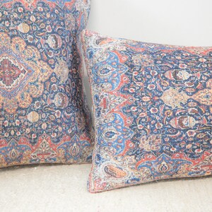 May include: Two decorative throw pillows with a blue, red, and yellow paisley pattern.
