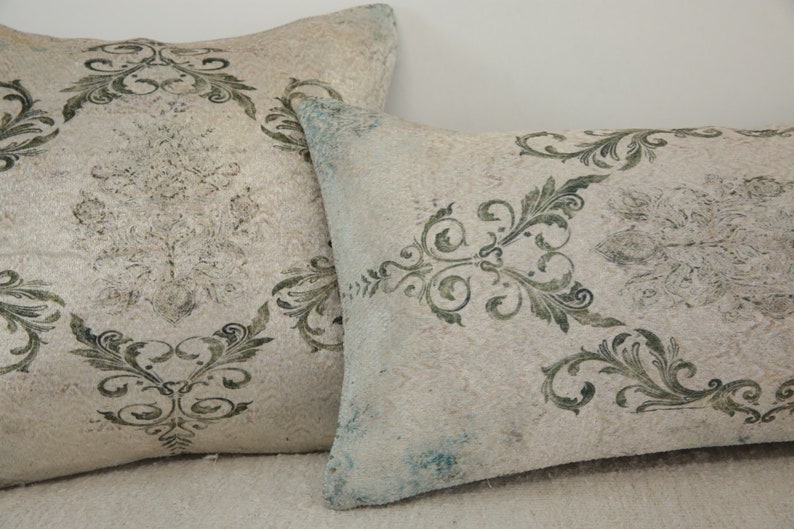 Puede incluir: Dos almohadas decorativas con fondo blanco y un patr&oacute;n floral verde.