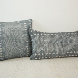 May include: Two decorative throw pillows with a geometric pattern in shades of blue and white.