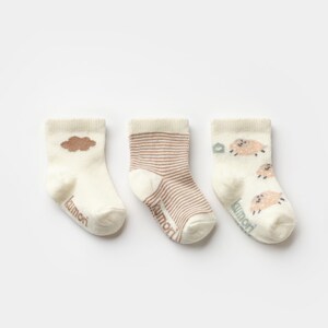 May include: Three pairs of baby socks in cream, brown, and tan. One pair features a brown cloud, another has brown stripes, and the third has sheep illustrations. The word "kumori" is printed on each sock.