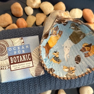 May include: A bar of shea butter soap with a blue and white label that says "Ocean Pur Botanic" and "Shea butter soap net wt. 1.9oz 53g". The soap is sitting on a blue towel with a seashell on top of the towel.