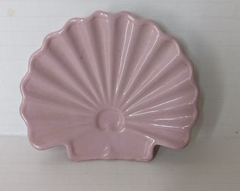 May include: A pink ceramic seashell dish. The dish is shaped like a seashell with a scalloped edge and a smooth, glossy finish.