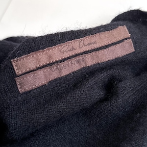 May include: Close-up of a black garment with a brown label. The label has the text "Rick Owens" and "CABBY F/W06" printed on it. The fabric appears to be a soft knit material.