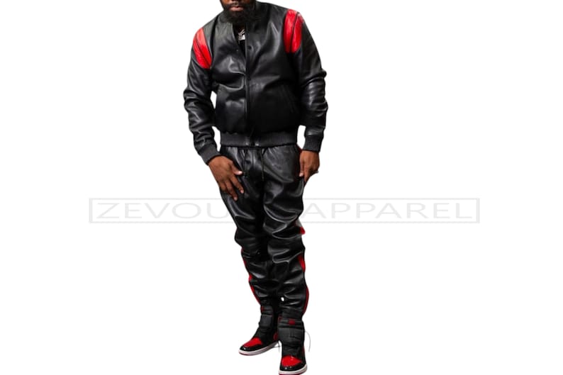 May include: Black leather bomber jacket and matching pants with red accents. The jacket has red shoulder patches, and the pants have a red stripe down the side. The outfit is part of the ZEVOU APPAREL collection.