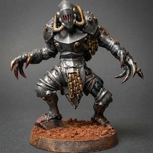 Puede incluir: Una figura en miniatura de una criatura metálica blindada con casco, manos con garras y tubos alrededor del cuello. La figura presenta un revestimiento plateado, detalles de cadenas doradas y acentos rojos en las garras sobre una base.