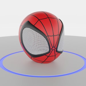 Puede incluir: Un altavoz rojo y negro con temática de Spider-Man con una rejilla de malla. El altavoz está sobre una superficie blanca con un anillo de luz azul a su alrededor.
