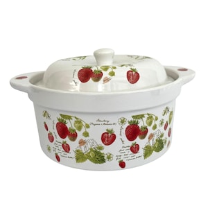 May include: A white ceramic casserole dish with a lid, featuring a botanical strawberry pattern with red berries, green leaves, and white flowers. The design includes the text Strawberry Fragaria x Ananassa and Royal Sovereign.