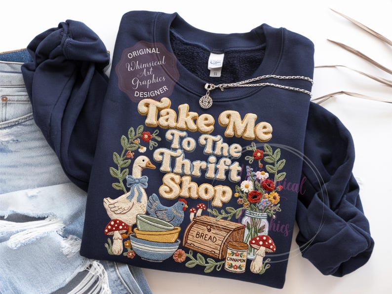 Puede incluir: Sudadera azul marino con el texto "Take Me To The Thrift Shop" en una fuente retro. El dise&ntilde;o incluye ilustraciones de un ganso, una gallina, setas, cuencos, pan y flores. Una cadena de plata con un colgante est&aacute; encima.