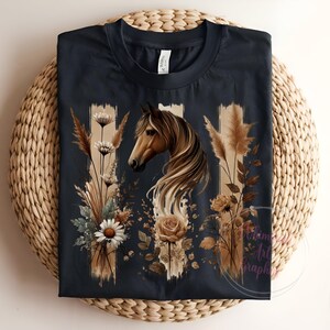 May include: A dark blue t-shirt with a graphic print of a brown horse's head with a flowing mane, surrounded by dried flowers and grasses. The design is in shades of brown, beige, and white.