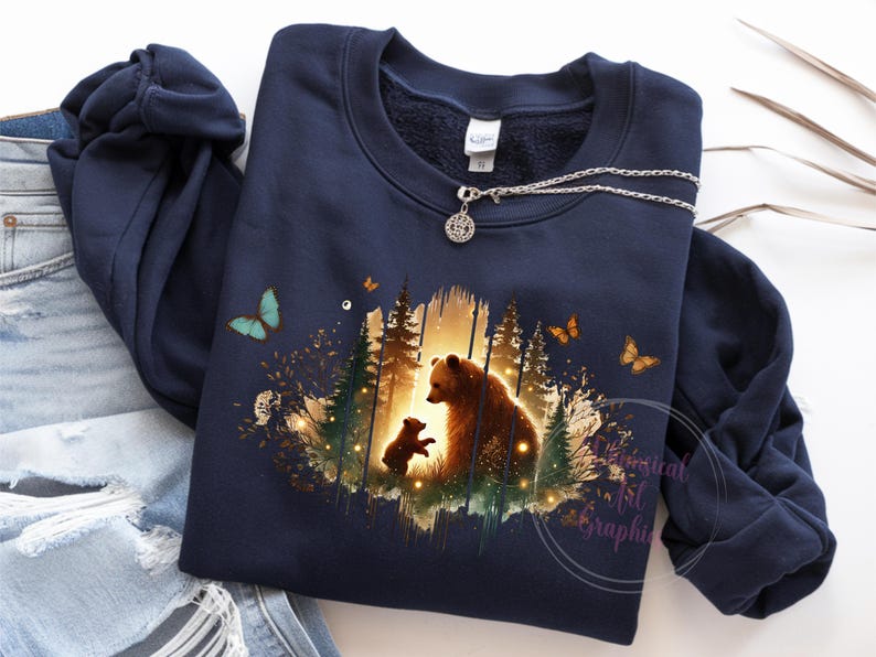 May include: A navy blue sweatshirt with a graphic print of a mother bear and her cub standing in a forest setting. The graphic is surrounded by a watercolor-like effect and features butterflies.