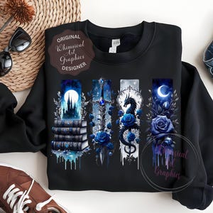 May include: Black sweatshirt featuring four vertical fantasy art panels with a castle, sword, dragon, and moon, all in shades of blue. The design includes blue roses and the text "Original Whimsical Art Graphics Designer".